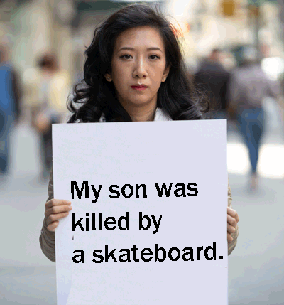 Sad and angry woman holding up a poster reading: 'My son was killed by a skateboard'